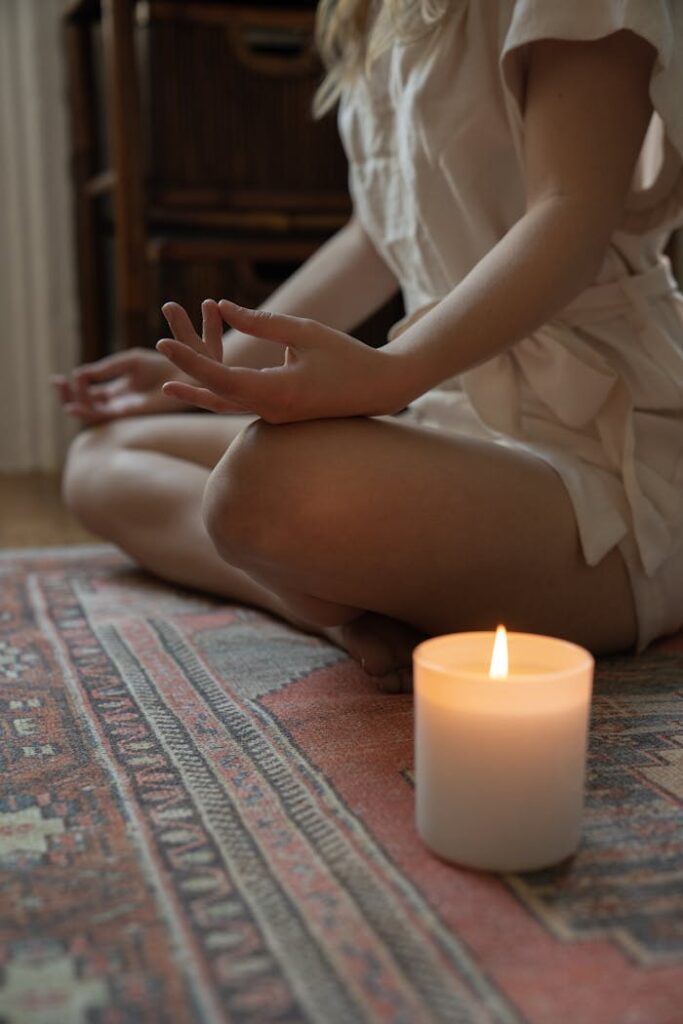 Woman Meditating Next to a Burning Candle 